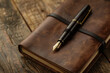 A high-end fountain pen resting on the textured surface of a closed, leather-bound notebook