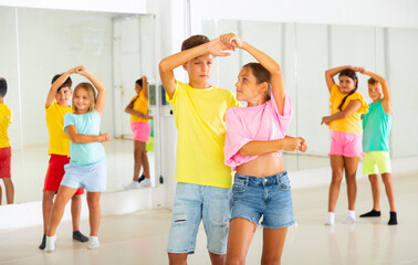 Wall Mural - Kids in pairs exercising salsa moves together during group dance class.