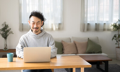 Wall Mural - テレワークでや自宅で仕事やパソコンをする笑顔の日本人(アジア人)男性のイメージ