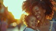 Happy black mother and child laughing | A close up portrait of a smiling African American woman with curly hair holding her little daughter while walking on the street at sunset | Mother's day