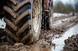 Tractor tires in mud. A heavy truck driving with sludge underneath its wheels. Mud splashing. Environmental awareness. Soggy soil. Rubber. Climate. Machinery. Agriculture. Construction site. Sleet