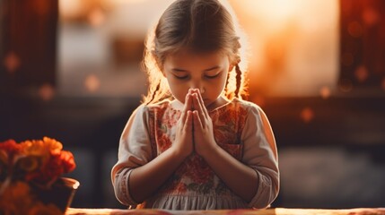 Wall Mural - A young girl praying at a table, suitable for religious and spiritual concepts