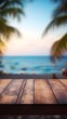 © Maria Shchipakina - wooden table set against a blurred tropical beach paradise at sunset, with bokeh lights and the silhouette of palm trees creating a tranquil and inviting backdrop