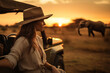 a woman watching the sunset from an all-terrain car in the African savannah with animals walking in the distance