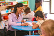 © Monkey Business - Female Primary Or Elementary School Teacher Helping Students At Desks In Multi-Cultural Class
