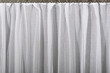 The white tulle curtain hangs in folds. The waves of the fabric are transparent and clean.