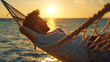 Young man lying in a hammock by the ocean and sunset view. A handsome guy is resting in a hammock against the backdrop of the mountains by the sea.