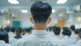 Fototapeta  - A teacher's back view with rows of students in uniforms facing a blackboard.