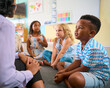 © Monkey Business - Multi-Cultural Primary Or Elementary School Class Sitting On Floor Listening To Teacher In Classroom