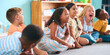 © Monkey Business - Line Of Smiling Primary Or Elementary School Students Sitting On Floor During Classroom Lesson