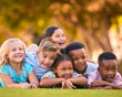 © Monkey Business - Portrait Of Multi-Cultural Primary Or Elementary School Student Friends Lying On Grass Outdoors