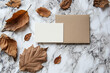 A white background with a brown box and a bunch of leaves and pine cones. Scene is warm and cozy, with a touch of nature