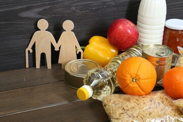 Wall Mural - Humanitarian aid for elderly people. Different donation food and figures of couple on wooden table, closeup