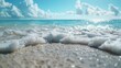 A tranquil beach setting under a clear sky, showcasing gentle waves lapping onto the sandy shore, creating a frothy foam as the water withdraws back into the turquoise sea