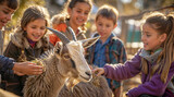 Fototapeta Zwierzęta - Group of happy children are feeding a domestic goat in a petting zoo