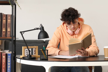 Poster - Male student reading book at table in library