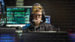 Cyber attack vishing text in foreground screen, anonymous hacker hidden with hoodie in the blurred background. Vulnerability text in binary system code on editor program.