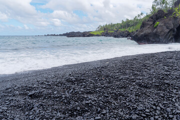 Landscape view of the amazing Honokalani Black Sand Beach in Waianapanapa State Park on the island of Maui Hawaii, USA