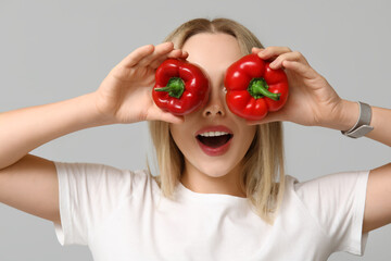 Wall Mural - Young woman with bell peppers on light background, closeup
