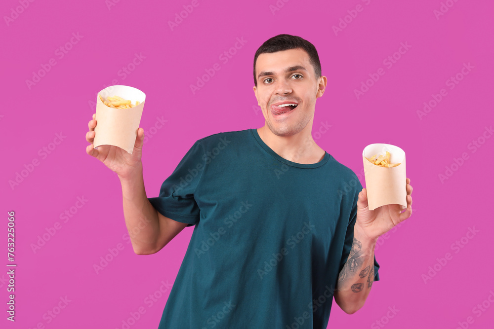 Young man with french fries on purple background