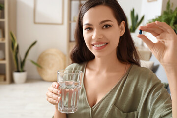 Canvas Print - Young woman with glass of water and pill at home