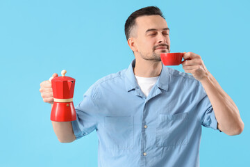 Poster - Handsome man with geyser coffee maker drinking espresso on blue background