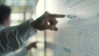 © VK Studio - Close-up of a finger pointing to specific data on a bright, complex project timeline chart.