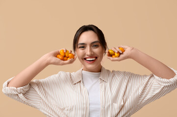 Poster - Beautiful young woman with tasty kumquat fruits on beige background