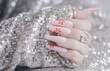 Beautiful pink manicure. Stylish pastel pink manicure with candy. Nail polish. Art nails. Candy nails. Female hands manicure close up on sequin background