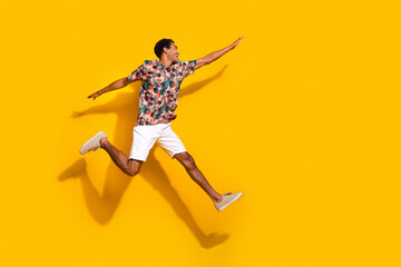 Wall Mural - Full length photo of excited cheerful man wear print t-shirt jumping high flying empty space isolated yellow color background