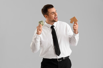 Wall Mural - Male realtor with money and wooden house on light background