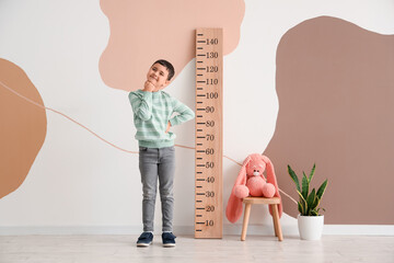 Sticker - Thoughtful little boy standing near wooden stadiometer at home