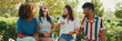 © Andrii Nekrasov - Happy multiethnic young people talking while sitting on park bench on summer day outdoors, Panorama. Group of friends talking and laughing merrily in city park