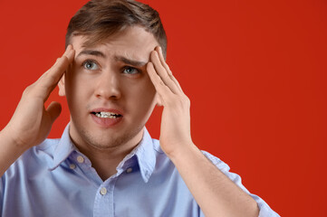 Canvas Print - Young man suffering from headache on red background, closeup