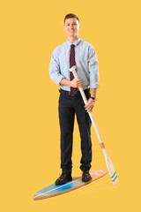 Poster - Funny businessman with paddle and surfboard on yellow background