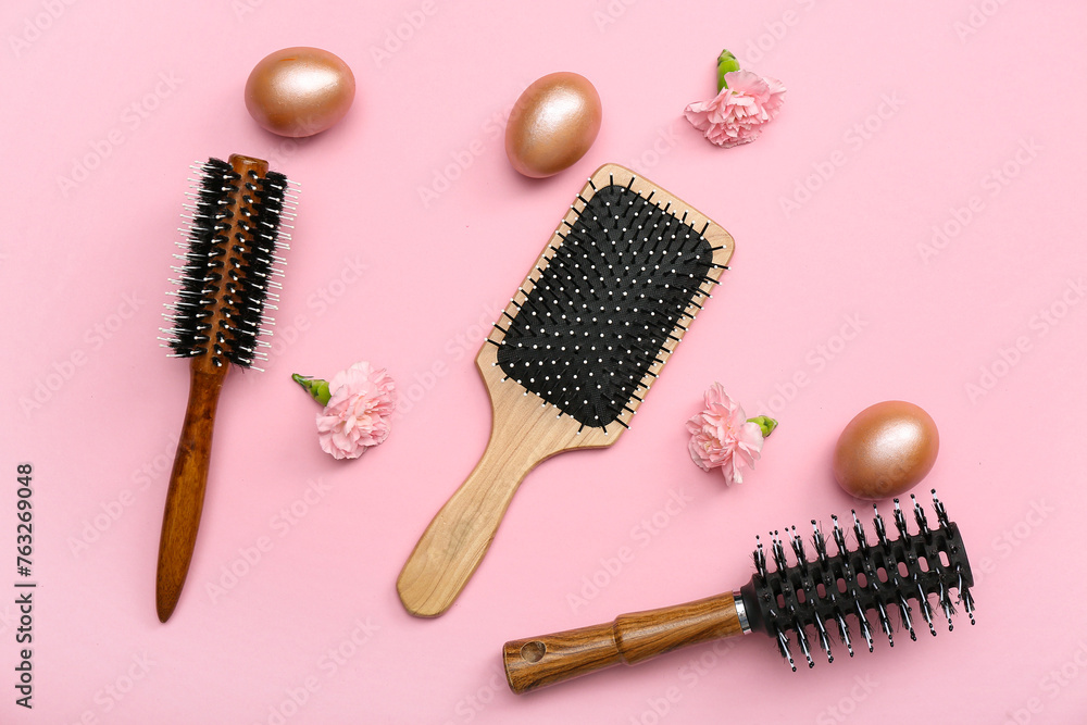 Hair brushes with flowers and Easter eggs on pink background