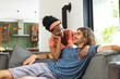 A diverse couple relaxes on a gray sofa at home, sharing a moment