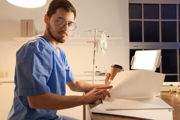 Sticker - Male nurse with cup of coffee studying at hospital in evening