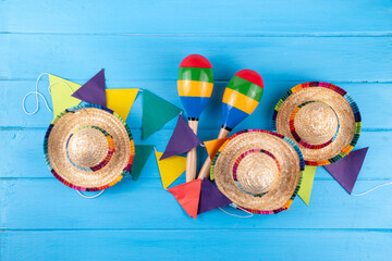 Wall Mural - Mexican holiday background with serape striped blanket or poncho, sombrero hat, maracas on old blue wood backdrop. Mexico Cinco de Mayo festival, Mexican Independence day background