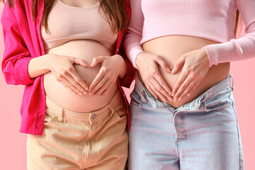 Wall Mural - Pregnant female friends on pink background, closeup