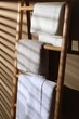 Terry towels on wooden decorative ladder near beige wall