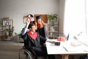 Wall Mural - Male graduate in wheelchair with diploma and classmate video chatting at home