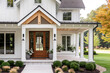 © Joseph Hendrickson - A front door detail of a white modern farmhouse with a wooden front door, black light fixtures, white oak accents, and a covered porch.