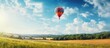 A red and blue hot air balloon soaring above a meadow