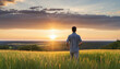 rear view carefree freedom successful male standing confident looking at the end of skyline in the grass field meadow landscape summertime sunset moment nature background