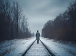 lonely man walking down train tracks on a cold winter day
