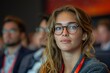 © Larisa AI - Focused young woman with glasses attending a conference, people in soft focus behind