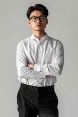 Wall Mural - Asian man is standing, wearing a white shirt and black pants, against a plain background
