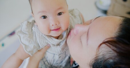 Poster - A woman is holding a baby and kissing its face