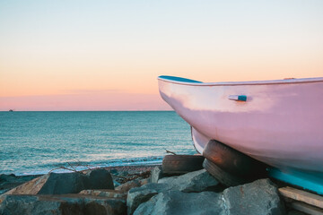 Wall Mural - A simple painted wooden boat on the seashore during sunset. Boat on the shore of the Black Sea.